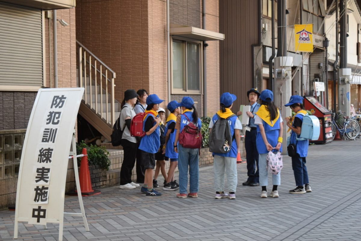「防犯訓練実施中」の看板と、訓練に参加した子どもたち(円頓寺商店街)